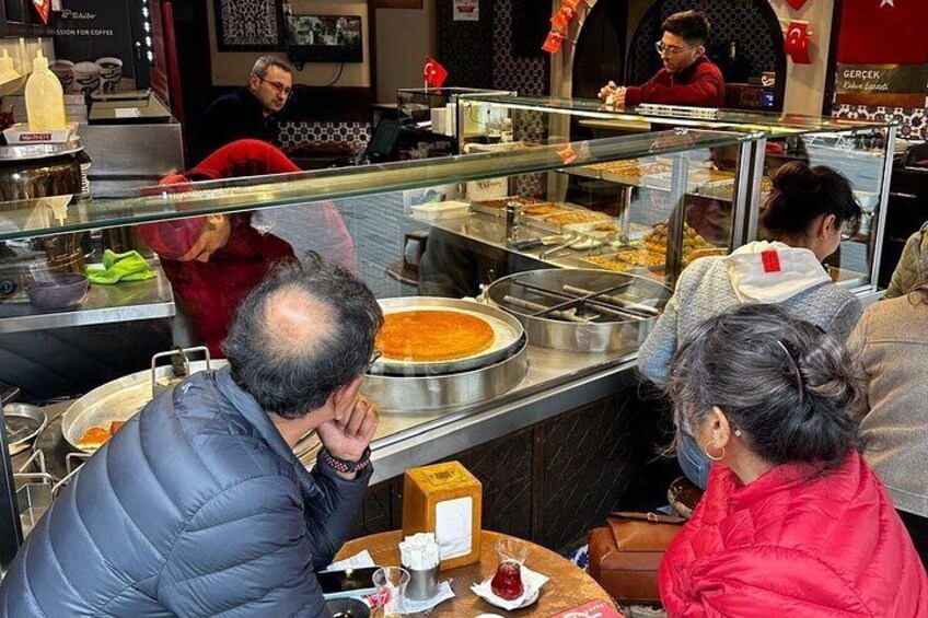 A food court with people eating and a man in a blue jacket. 4