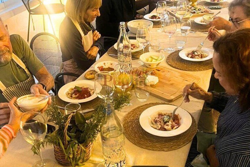 A group of people dining at a table with various dishes, glasses, and a bottle. 4