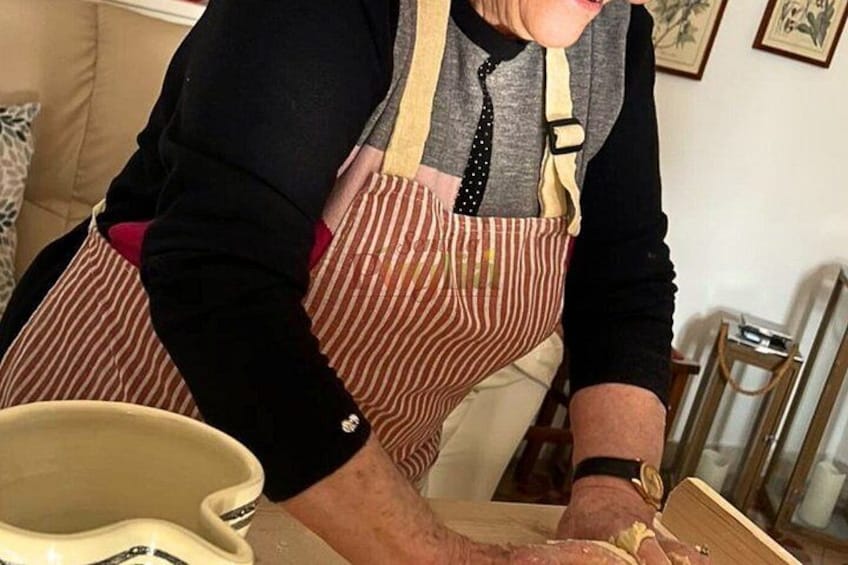 A person wearing a striped apron, working with dough on a table. 5