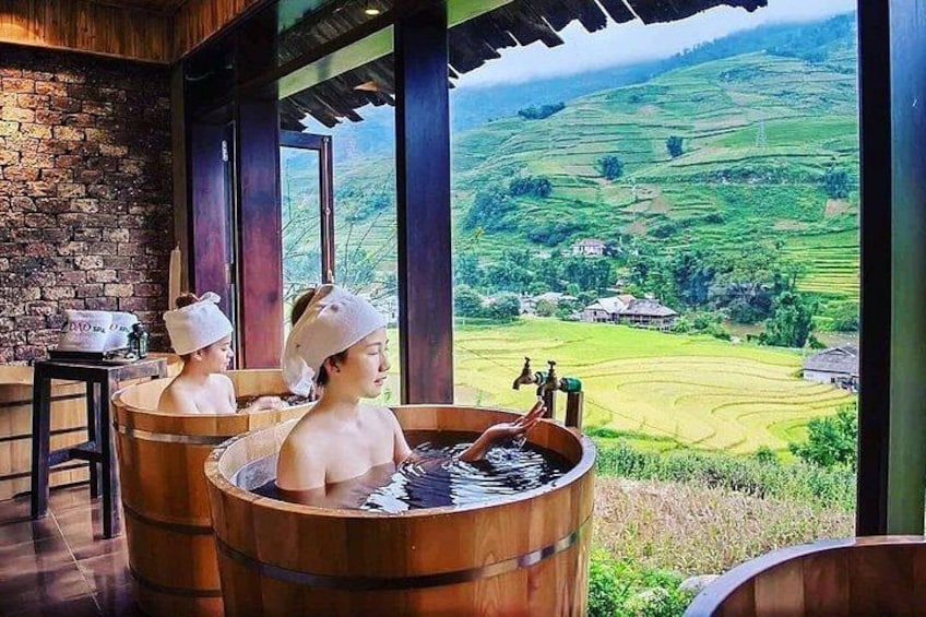 Two people in wooden tubs with a view of terraced fields. 2