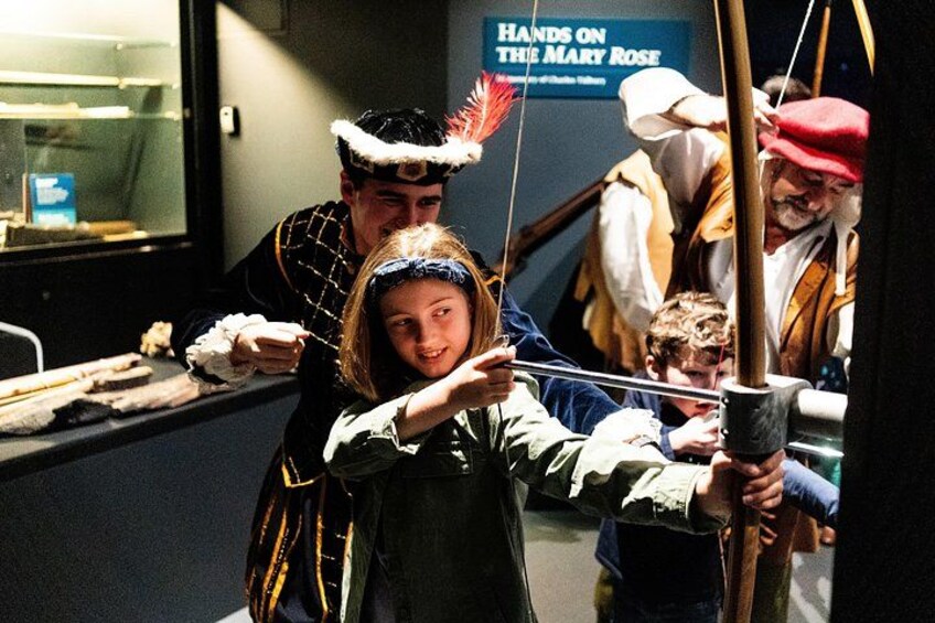 A person in a historical costume aiming an arrow at a target. 3