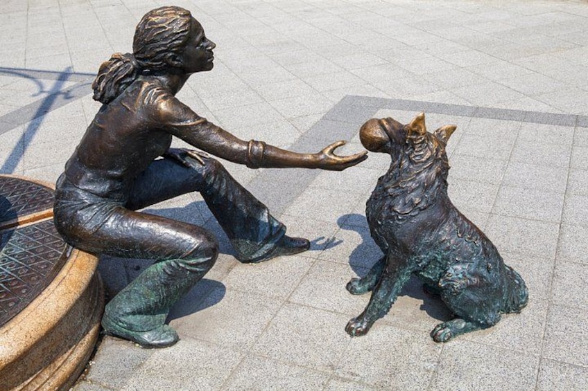 Una statua in bronzo raffigura una persona e un cane seduti. 3