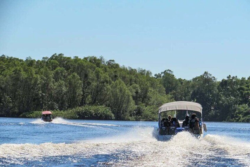 A boat speeding across a river with a forested shoreline in the background. 2