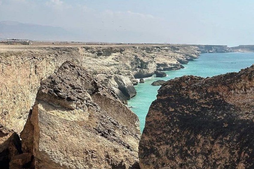 Eine Küstenlandschaft mit zerklüfteten Klippen und blauem Meer. 3