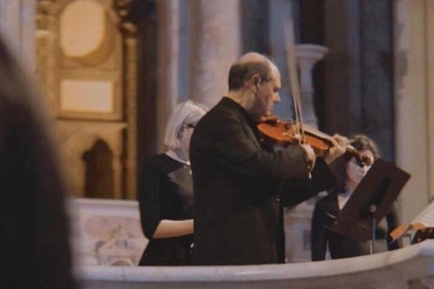 A person playing a violin in a church setting. 2