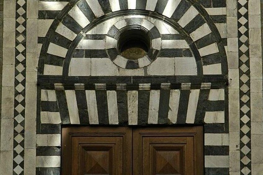 Una entrada de edificio con un arco a rayas blancas y negras y puertas de madera. 2