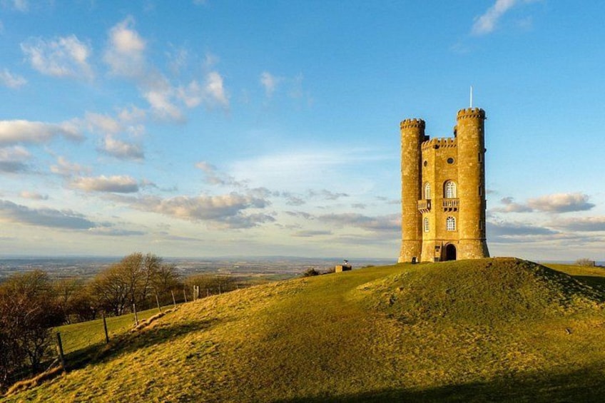 A historic tower on a grassy hill with a clear sky. 5
