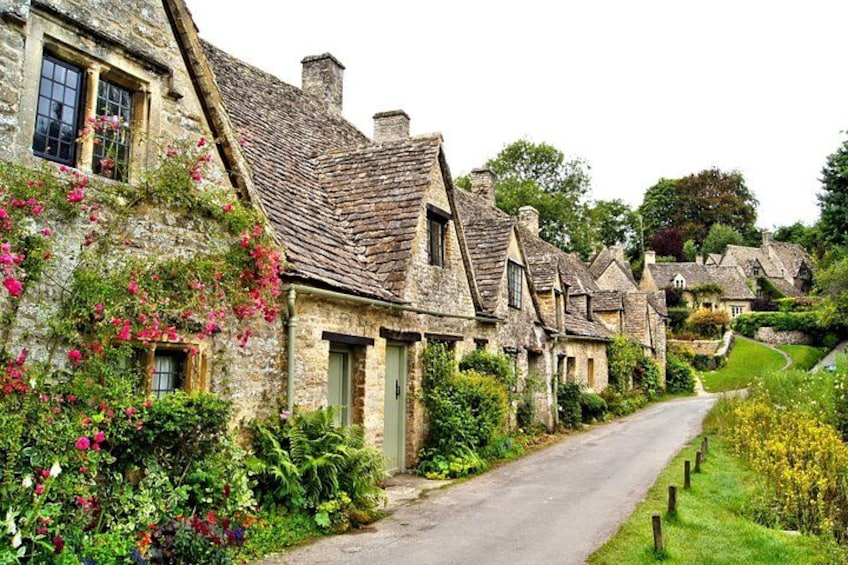 A row of stone cottages with flower boxes and a narrow road. 2
