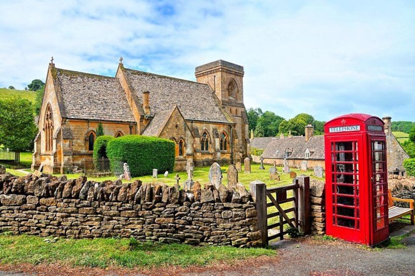 A church with a stone wall, a red telephone booth, and a stone gate. 1