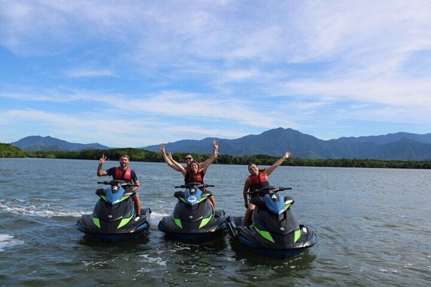 Drie personen waterskieren op een meer, met bergen op de achtergrond. 3
