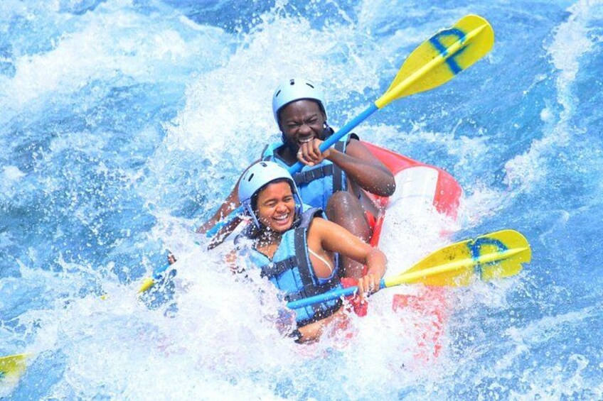 Two people kayaking on a river with white helmets and life jackets. 2
