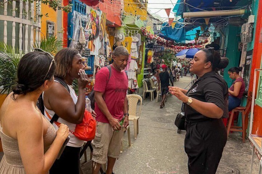 Una calle estrecha con edificios de colores y gente caminando. 3