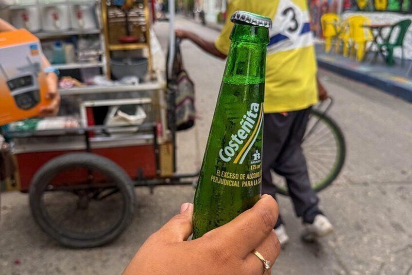 Una mano sosteniendo una botella verde con etiqueta. 4