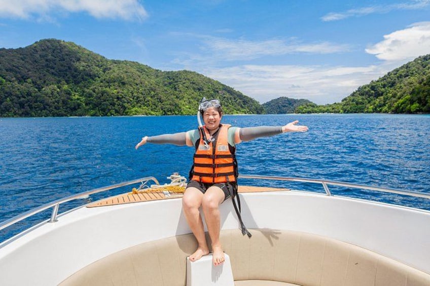 A person on a boat with a life jacket, surrounded by a calm lake and green hills. 1