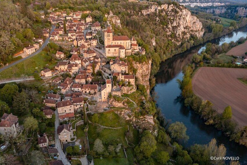 Une ville nichée dans une vallée, traversée par une rivière, entourée de verdure et dominée par une imposante construction qui ressemble à un château. 5