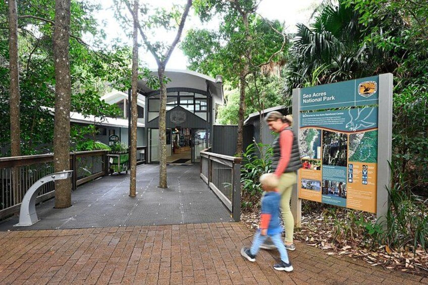A pathway leading to a building with a sign for Sea Acres National Park. 2