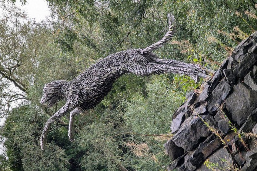 Una escultura grande y detallada de un dinosaurio en un entorno natural. 1