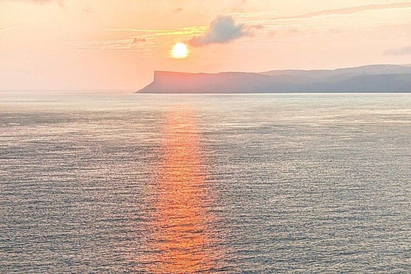 Un atardecer sobre un mar tranquilo con una masa de tierra a lo lejos. 3