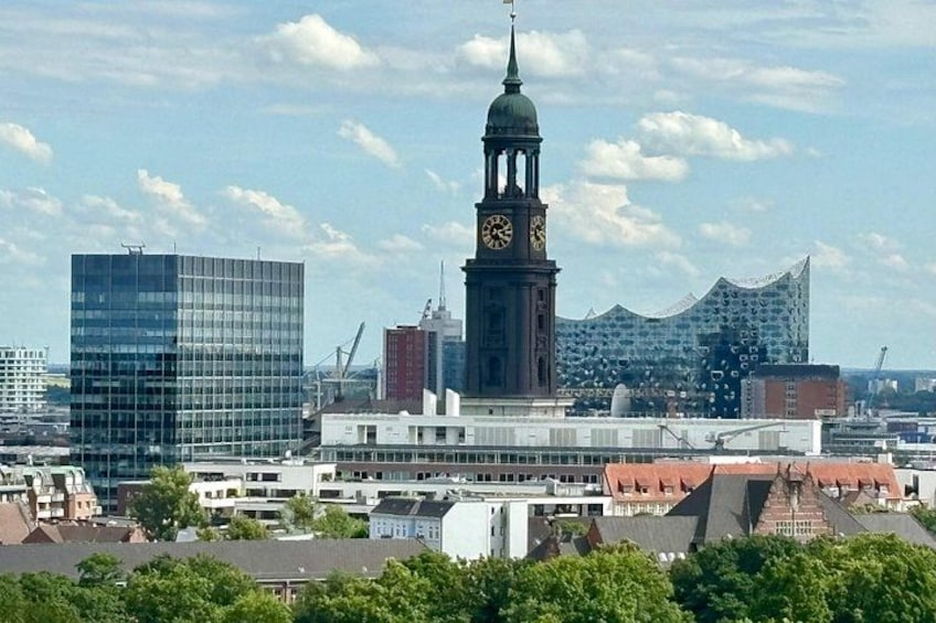 En stadsbild med ett framträdande klocktorn, moderna byggnader och en blandning av olika arkitektoniska stilar. 1