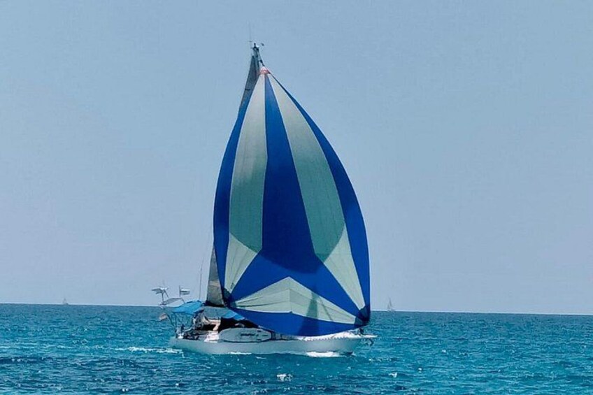 Een zeilboot met een blauw-wit zeil op de oceaan. 1