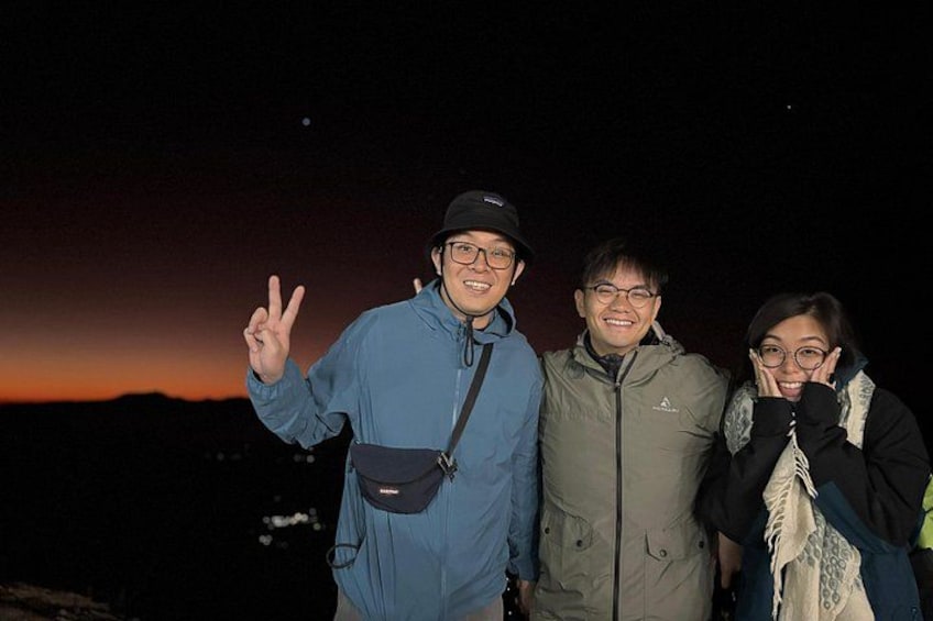 Three people outdoors at night with a sunset in the background. 2