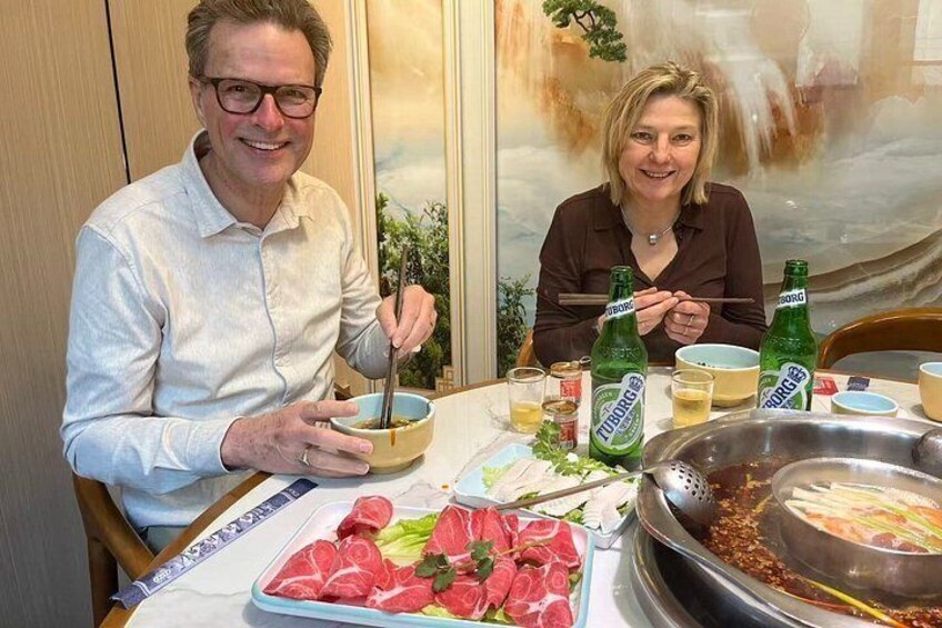 Two people dining at a table with a variety of foods and drinks. 3
