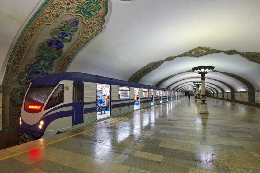Una moderna stazione ferroviaria con un treno elegante, decorazioni elaborate al soffitto e un pavimento pulito rivestito di piastrelle. 2