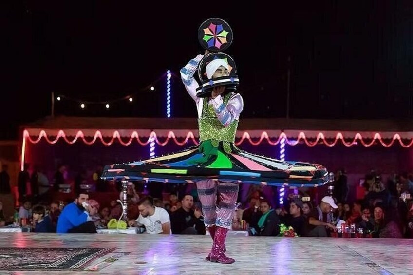 A person performing an acrobatic act with a colorful hoop on a stage. 5