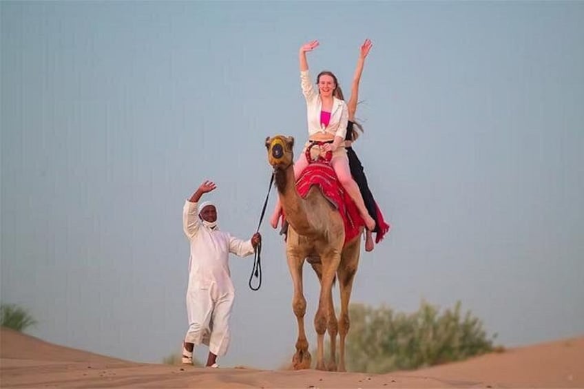 A camel with a woman and a man in desert attire. 2