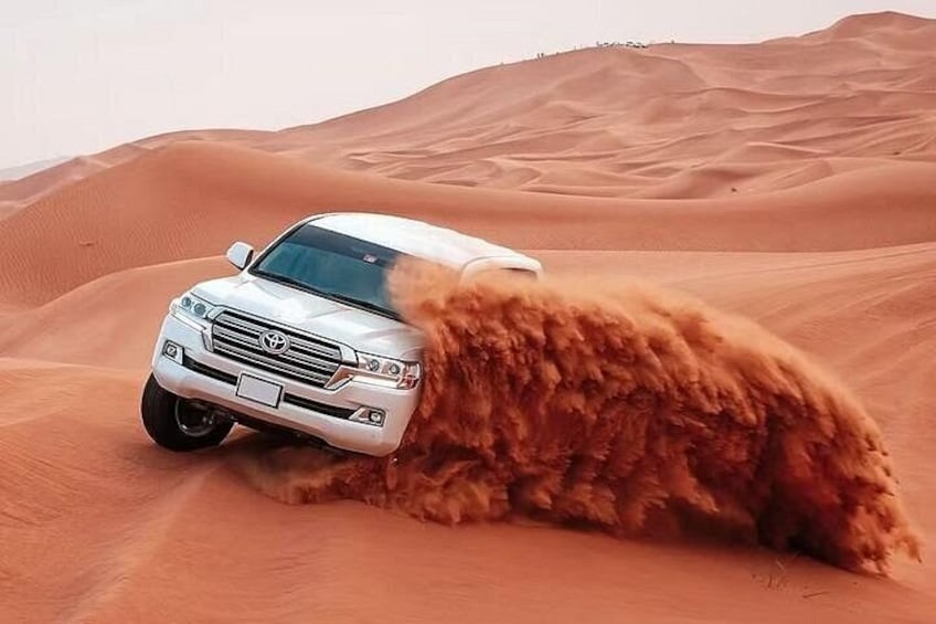A white SUV driving through a desert with sand dunes. 4