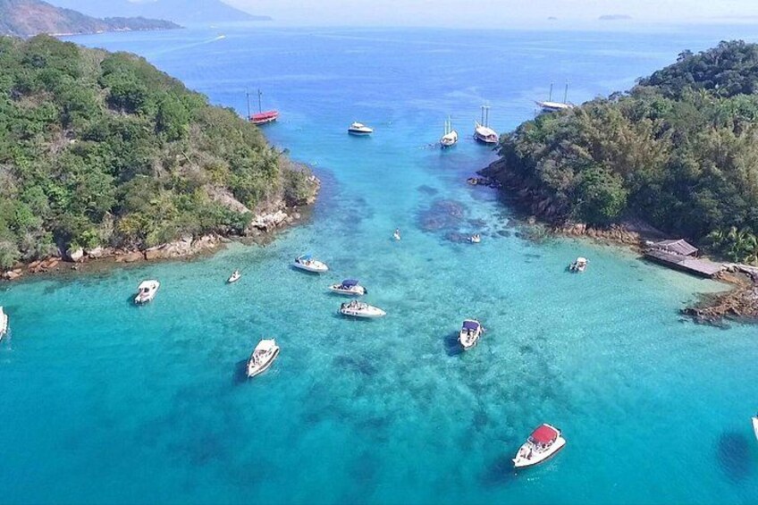 Una zona costera con aguas turquesas cristalinas, varios barcos y colinas verdes exuberantes. 4