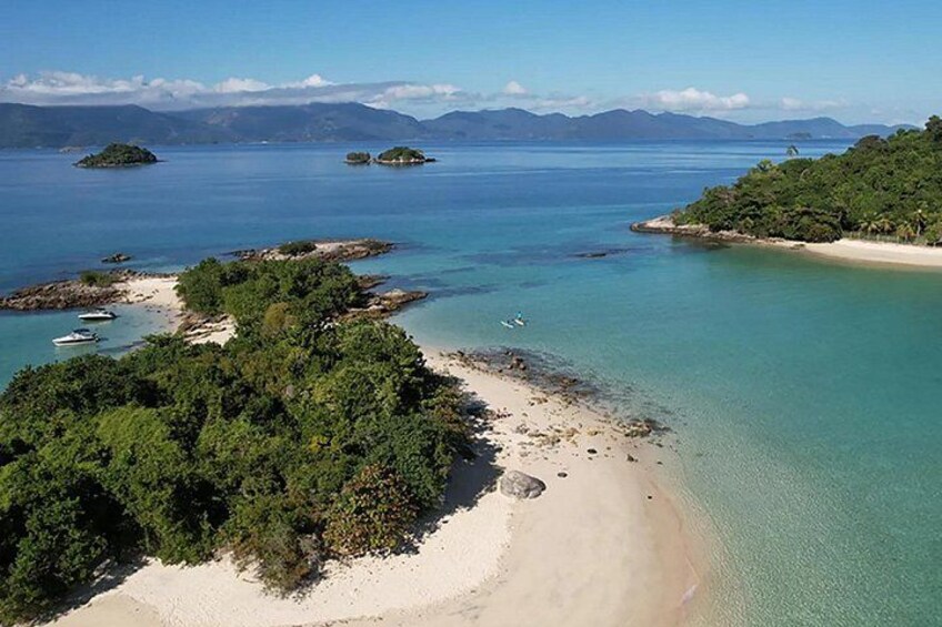 Un paisaje costero con una playa arenosa, aguas turquesas cristalinas y pequeñas islas a lo lejos. 4