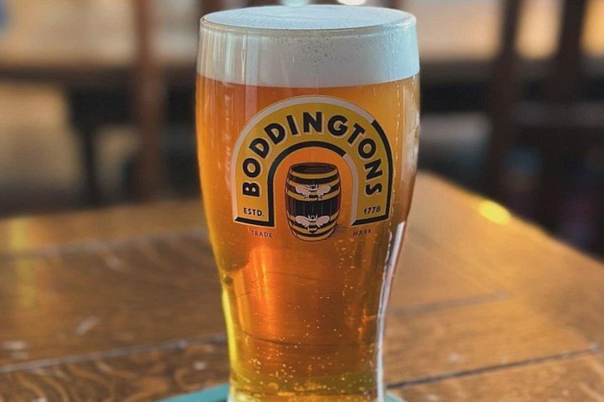 Et glas øl med et logo der viser 'BODDINGTONS' og årstallet '1778' på et træbord. 4