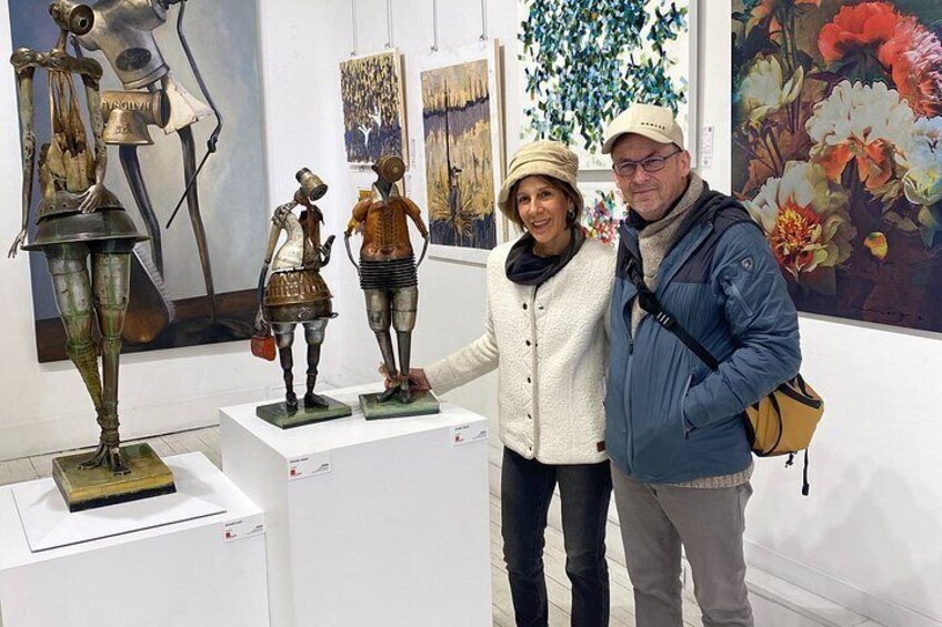 Interno di un museo con sculture esposte, una donna e un uomo che osservano e dipinti floreali alle pareti. 5