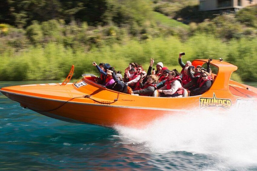 An orange speedboat with people wearing life jackets, labeled 'THUNDER,' moving through water. 2