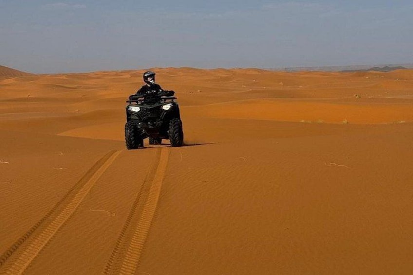 Een persoon rijdt op een quad door een zanderig woestijnlandschap. 3