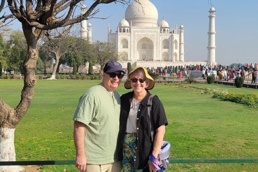 Due persone in primo piano di fronte al Taj Mahal, con una folla sullo sfondo. 1