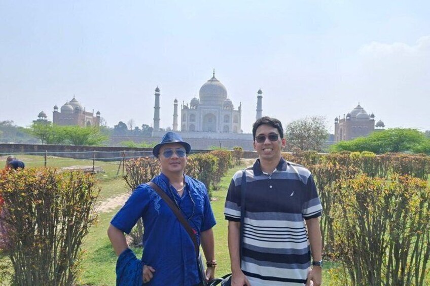 Due persone davanti al Taj Mahal, con un giardino e altre strutture storiche sullo sfondo. 3