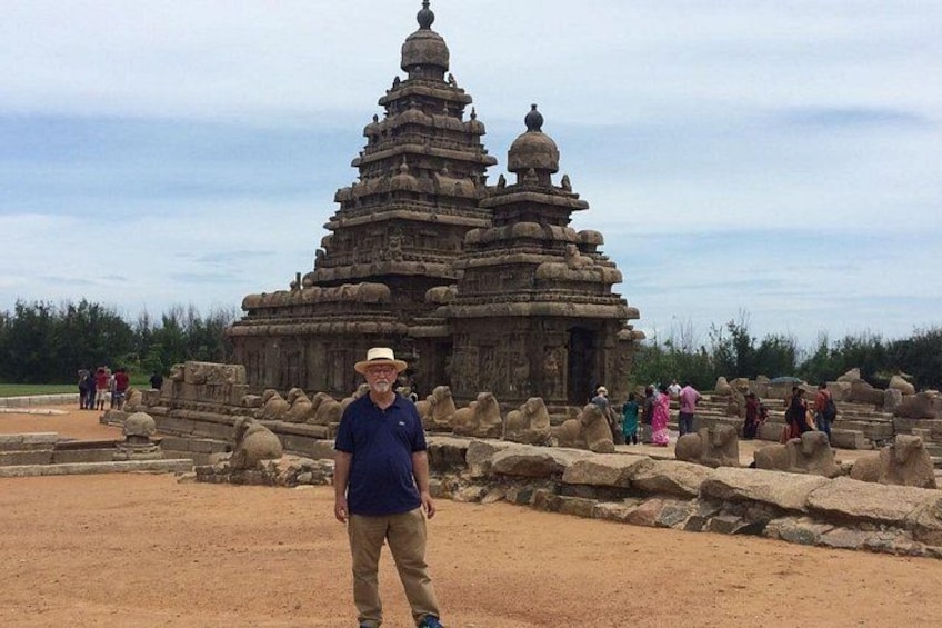 Un homme se tient devant un temple en pierre, dont le toit est constitué de plusieurs niveaux. 2