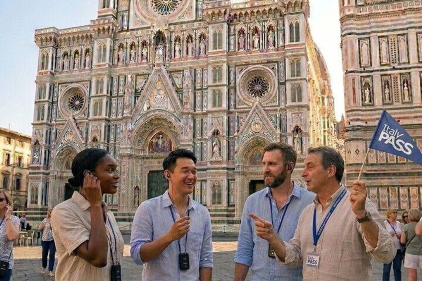 Un groupe de personnes se tient devant une grande cathédrale richement décorée, dont l’architecture présente de nombreux détails complexes. 1