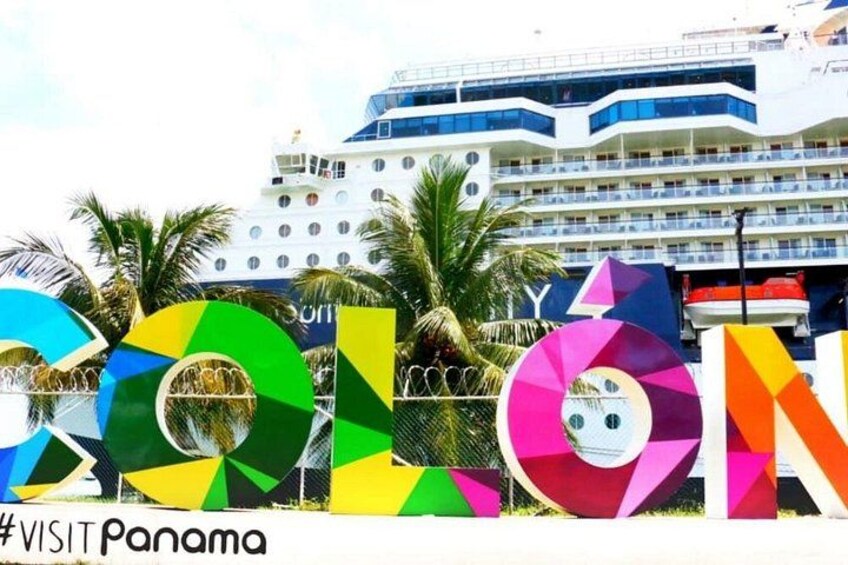 Un crucero con letras de colores que deletrean 'COLONIA' y una palmera al fondo. 3