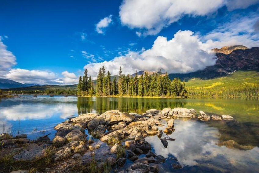 A calm lake with clear reflections, surrounded by mountains and dense forests. 3