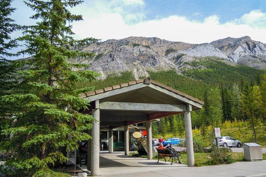 A mountain lodge with a covered entrance, parked cars, and a mountainous backdrop. 4