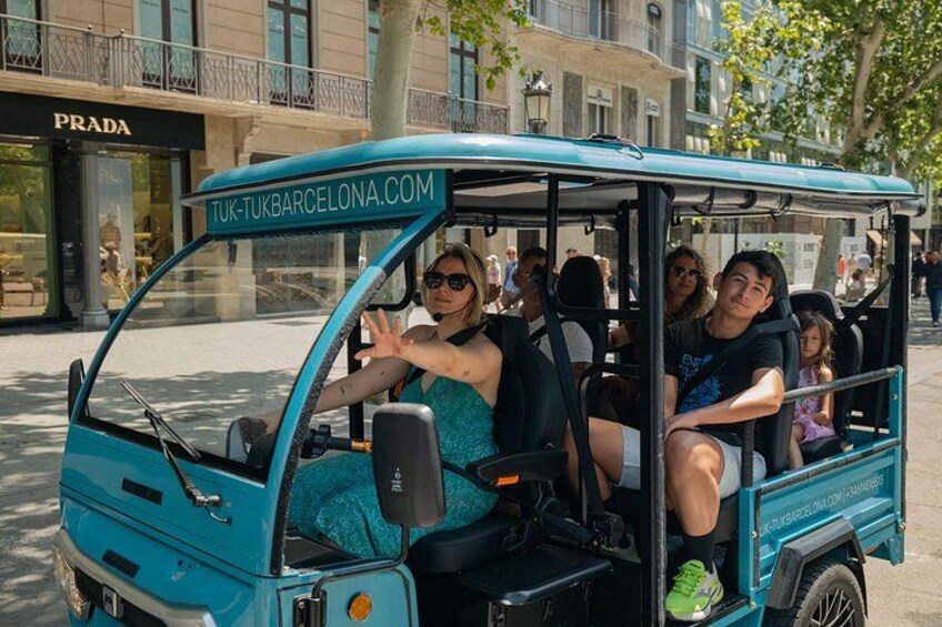 Een turquoise tuk-tuk met passagiers, geparkeerd op een stadsweg met gebouwen op de achtergrond. 4