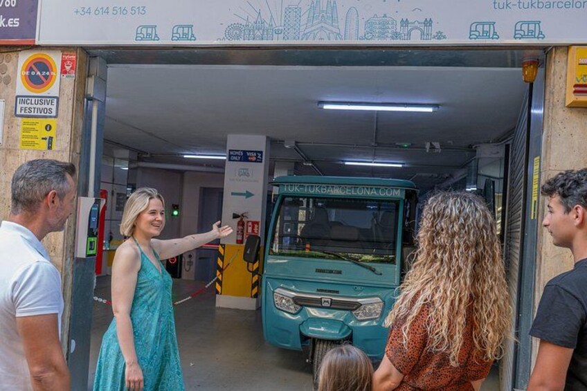 A bus station with a bus labeled 'TUK-TUK BARCELONA.COM' and a sign indicating 'INCLUSIVE FESTIVOS.' 3