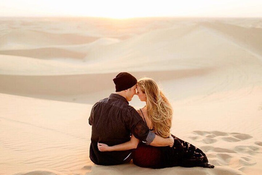 Un couple est assis sur une dune de sable, dans un paysage désertique. 2