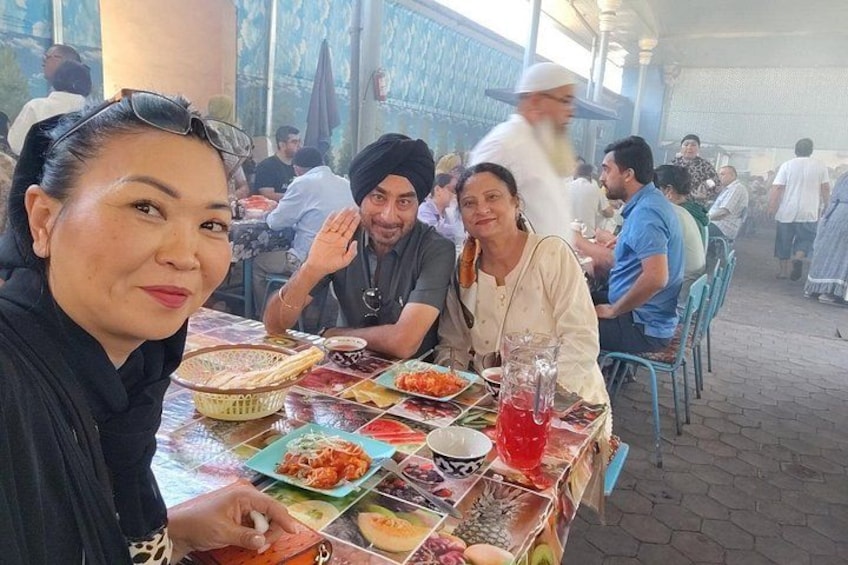 Un grupo de personas cenando en un restaurante al aire libre, con diversos platos y bebidas sobre la mesa. 4