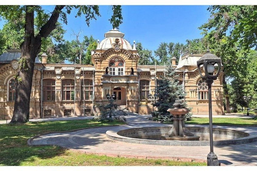 Un edificio histórico con arquitectura ornamentada, una fuente y un jardín bien cuidado. 2