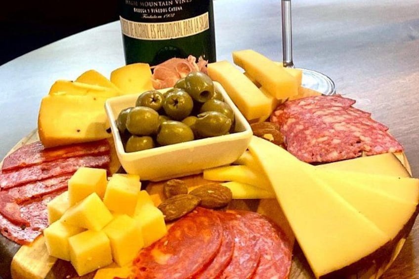 A charcuterie board with various cheeses, meats, and olives. 2