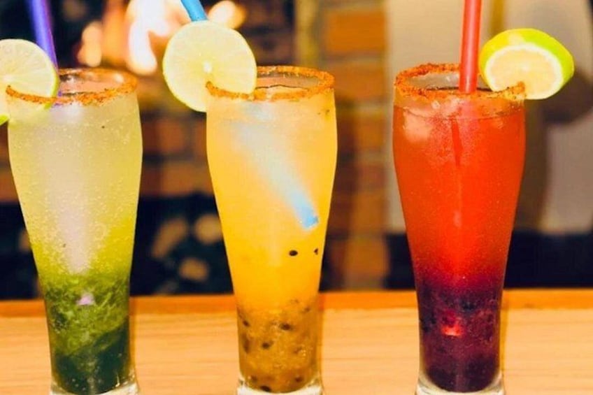 Three colorful cocktails with lime wedges and straws. 3
